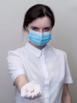 Doctor giving pills, woman in medical mask and gloves. The concept of the dose of drugs, vitamins, medical examination, coronavirus, treatment of influenza