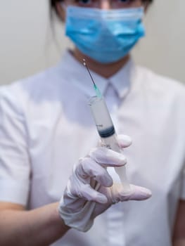 doctor holding a syringe in his hand. Woman in medical mask and gloves holds a syringe with medicine