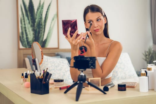 Young woman making beauty and cosmetic tutorial video content for social media. Beauty blogger smiles to camera while showing how to beauty care to audience or followers. Unveiling