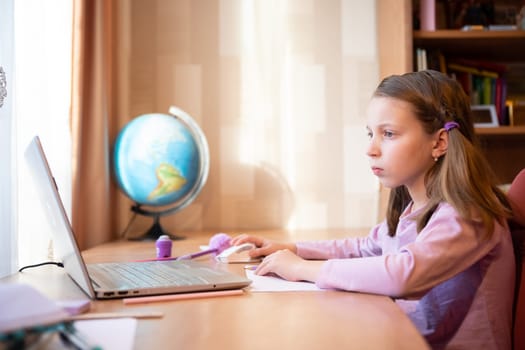 Online education of children. Girl schoolgirl teaches a lesson online using a laptop video chat call conference with a teacher at home.