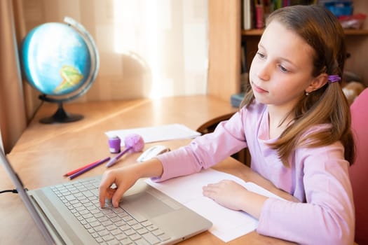 Online education of children. Girl schoolgirl teaches a lesson online using a laptop video chat call conference with a teacher at home.