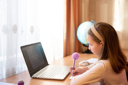 Online education of children. Girl schoolgirl teaches a lesson online using a laptop video chat call conference with a teacher at home.