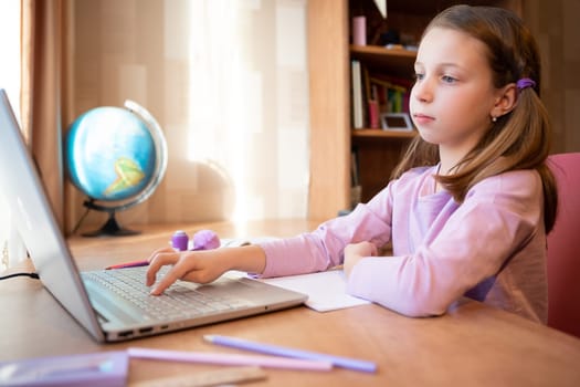 Online education of children. Girl schoolgirl teaches a lesson online using a laptop video chat call conference with a teacher at home.