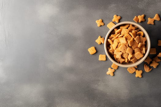 Bowl of crunchy fish-shaped crackers on a dark surface.