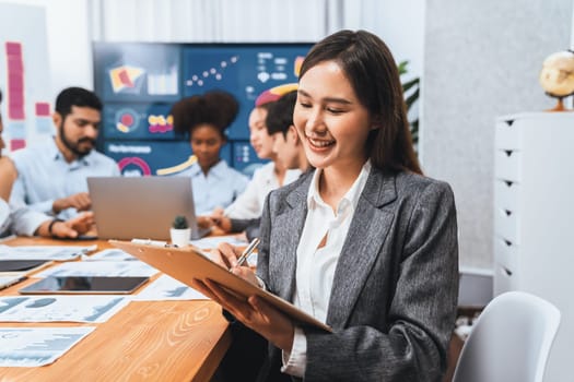 Portrait of happy young asian businesswoman with group of office worker on meeting with screen display business dashboard in background. Confident office lady at team meeting. Concord