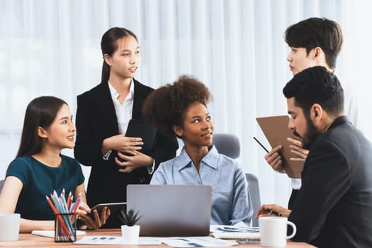 Multiracial analyst team use BI dashboard data to analyze financial report on meeting table. Group of diverse business people utilize data analysis by FIntech for success business marketing. Concord