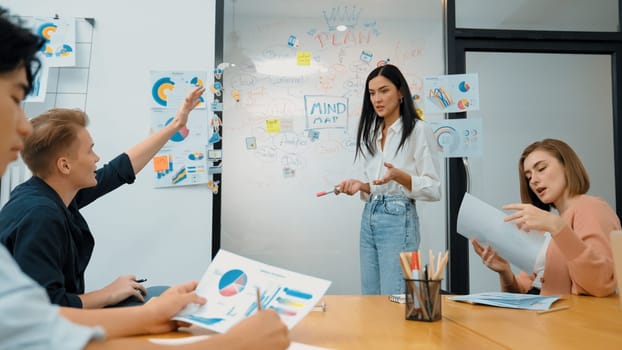 Closeup of young handsome caucasian raising hand and asking questions while young beautiful leader present business plan by using mind map and colorful graph between business meeting. Immaculate.