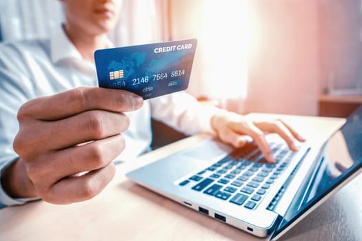 Young man use credit card for shopping payment online on laptop computer application or website. E-commerce and online shopping concept. uds