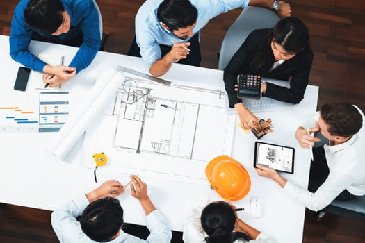 Top view banner of diverse group of civil engineer and client working together on architectural project, reviewing construction plan and building blueprint at meeting table. Prudent