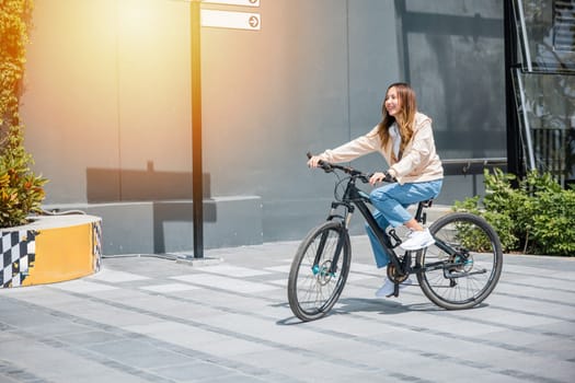 Happy Asian young woman riding bicycle on street outdoor near building city, Portrait of smiling female lifestyle use mountain bike in summer travel means of transportation, ECO friendly, Urban biking