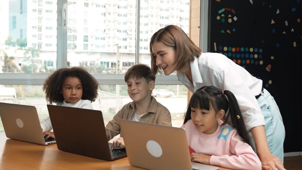 Smart teacher teaching and looking student using laptop at classroom. Professional instructor explained about programing engineering code or prompt while studying and learning program. Erudition.