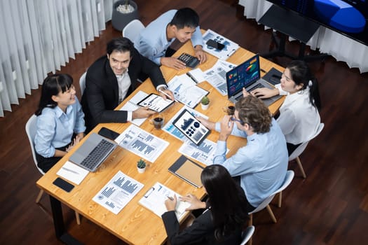 Wide top view of diverse group of business analyst team analyzing financial data report paper on meeting table. Chart and graph dashboard by business intelligence analysis. Meticulous