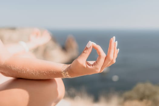 Woman meditating in yoga pose silhouette at the ocean, beach and rock mountains. Motivation and inspirational fit and exercising. Healthy lifestyle outdoors in nature, fitness concept.