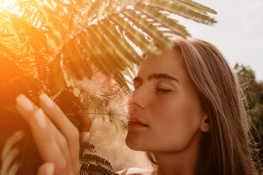 Beauty portrait of young woman closeup. Young girl smelling Chinese acacia pink blossoming flowers. Portrait of young woman in blooming spring, summer garden. Romantic vibe. Female and nature.