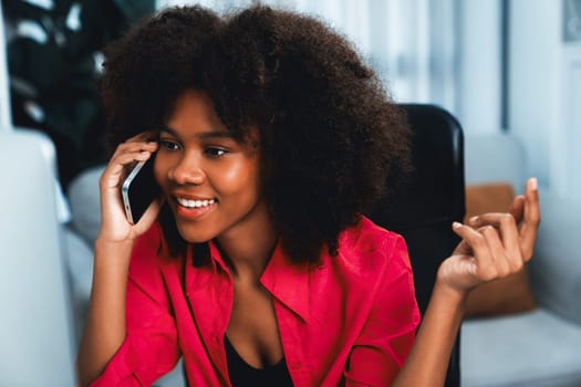 African woman talking with coworker or friend on the phone and looking at the screen with happy face. Achievement for promoting job position in the company with the good news life. Tastemaker.