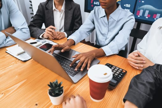 Multiracial analyst team use BI dashboard data to analyze financial report on meeting table. Group of diverse business people utilize data analysis by FIntech for success business marketing. Concord