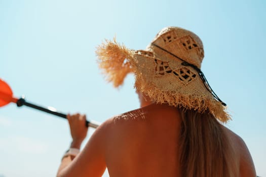 Woman in kayak back view. Happy woman with long hair in a swimsuit and hat floating in kayak on the sea. Summer holiday vacation. Summer holidays vacation at sea