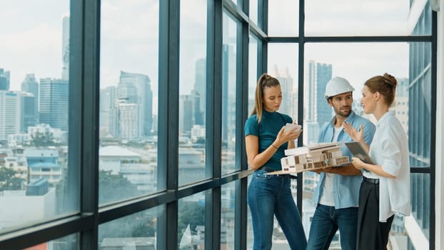 Skilled engineer holds house model and explain about house construction to skilled manager. Group of interior designer inspect architectural model. Working together, Civil engineering. Tracery