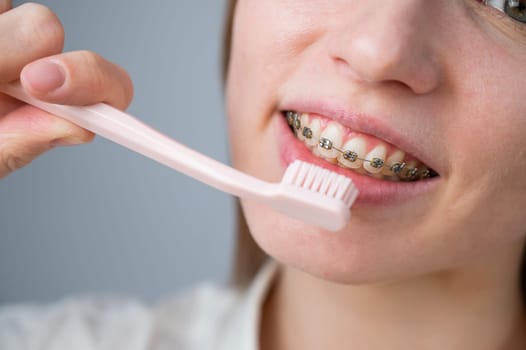 Portrait of a caucasian woman with braces on her teeth holding a toothbrush
