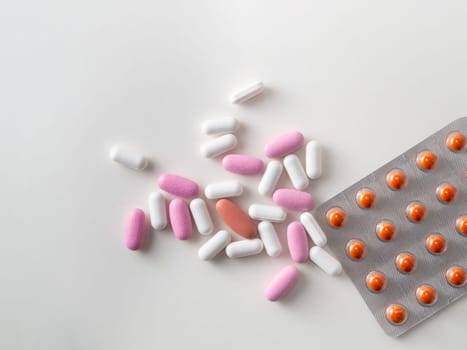 multicolored medical pills and packs of pills on a white table.