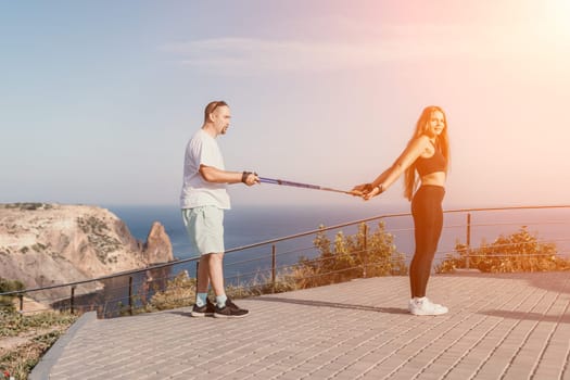 Happy Middle aged couple or friends practicing nordic walking in park near sea. Mature couple with trekking poles walking, practicing Nordic walking outdoors. Aging youthfully and sport concept.