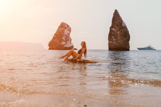 Woman travel sea. Young Happy woman in a long red dress posing on a beach near the sea on background of volcanic rocks, like in Iceland, sharing travel adventure journey