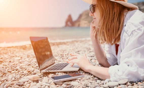 Woman sea laptop. Business woman in yellow hat working on laptop by sea. Close up on hands of pretty lady typing on computer outdoors summer day. Freelance, digital nomad, travel and holidays concept