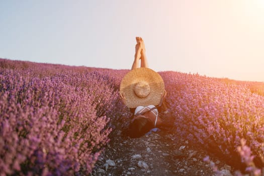 Selective focus. The girls legs stick out of the bushes, warm sunset light. Bushes of lavender purple in blossom, aromatic flowers at lavender fields.