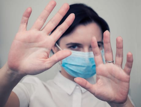 Masked woman makes stopping hand gesture. Stop coronavirus or covid 19 outbreak concept