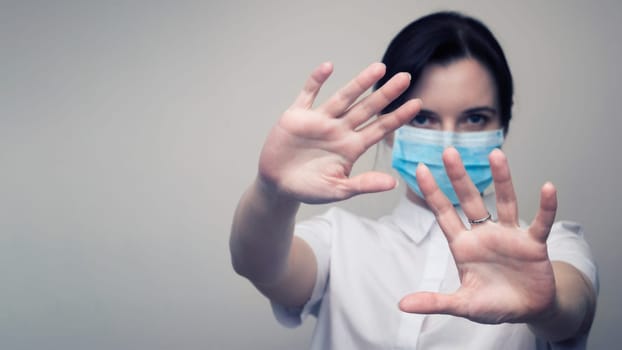 Masked woman makes stopping hand gesture. Stop coronavirus or covid 19 outbreak concept