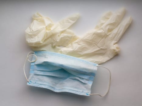 Used blue surgical protective masks and gloves. Medical trash. Used Coronavirus protection equipment on pink background. Used face masks and sterile glove. Covid-19