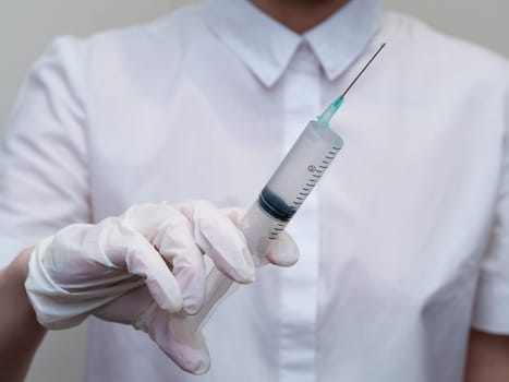 doctor holding a syringe in his hand. Woman in medical mask and gloves holds a syringe with medicine