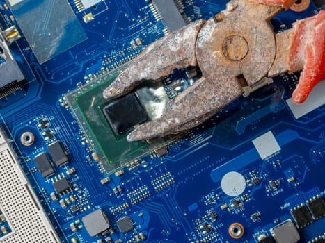 Computer repair concept. Old rusty passages on a blue laptop motherboard. The concept of unskilled work