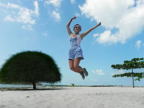 Young beautiful woman jumping in the beach