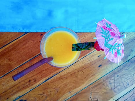 Fresh orange cocktail on wooden table. Blur beach on background