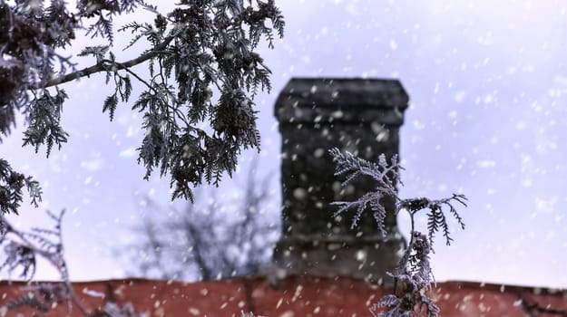 White smoke from the chimney of an old house during frost. Fireplace chimney on an iron roof.