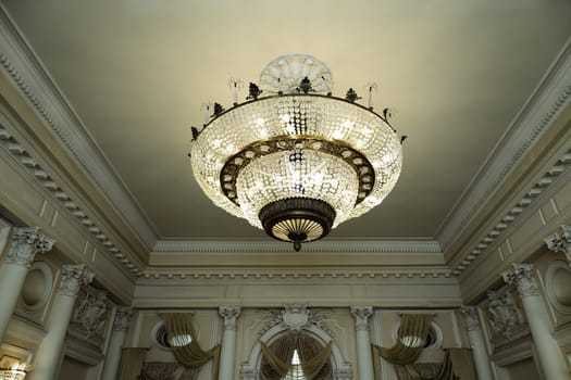 large round chandelier with crystals and candlesticks on the ceiling, dark background, retro style. High quality photo