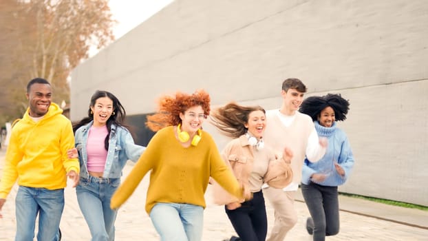 Diverse multiethnic friends laughing and running in the street