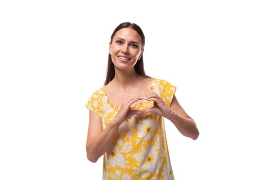 young pretty woman with straight black hair in a yellow sundress with a print pattern is happy.
