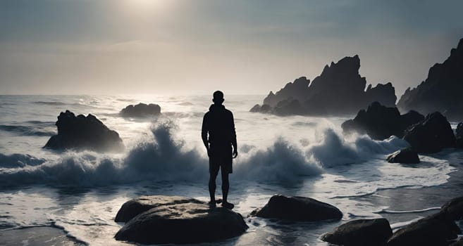 Silhouette of a man standing on the rocks in the sea.wave splash.human silhouette on the rocks on the seashore. Waves splashing on the rocks.