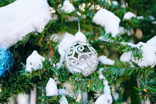 Decorated Christmas tree. Close-up of a blue bubble with snow on it hanging from a decorated Christmas tree.