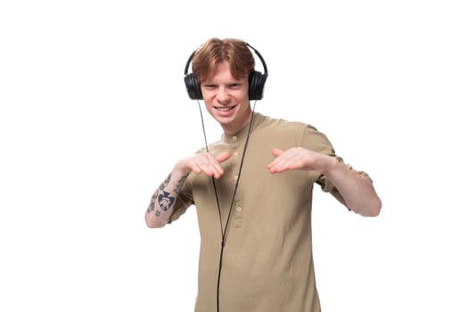 young cute caucasian guy with red hair dancing to music in headphones.