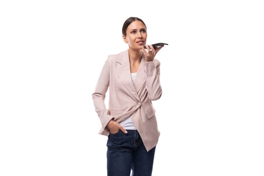 young confident caucasian woman with a ponytail hairstyle is dressed in a jacket and jeans calls by smartphone voice connection.