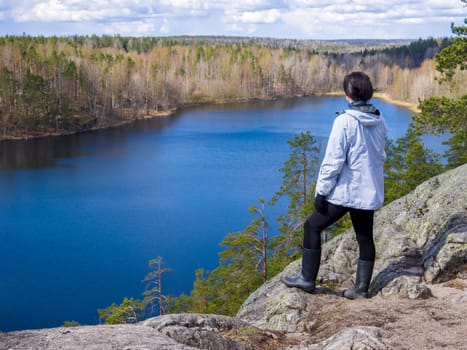 Girl tourist stands on a rock looks at the lake