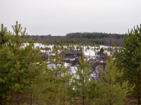 Village is in northern woods of Karelia, winter road with wooden house at evening. Russia