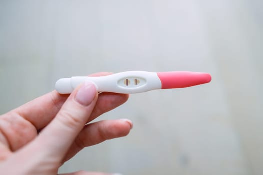 Woman hand holding positive pregnancy test with two lines on it. Pregnancy or fertility concept. High quality photo. High quality photo