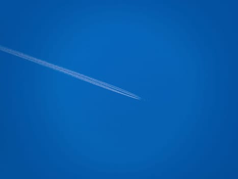 Beautiful picture of white plane flying with trail in blue sky