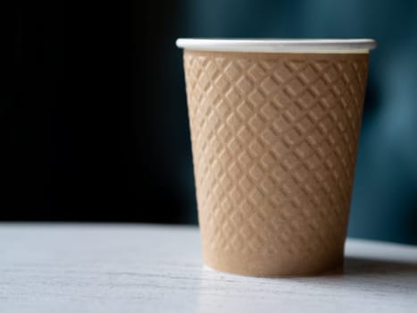 Take away a plastic cup of coffee on a wooden table with a blurred background with space for text or advertising.