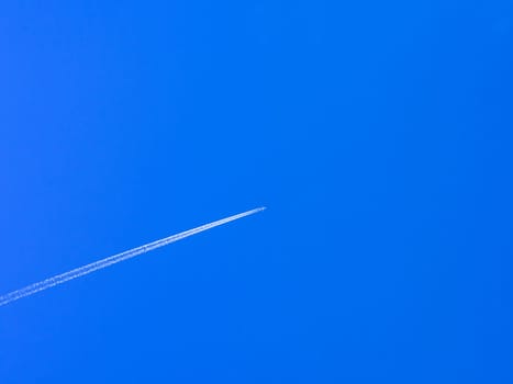 airplane contrail against clear blue sky with copy space