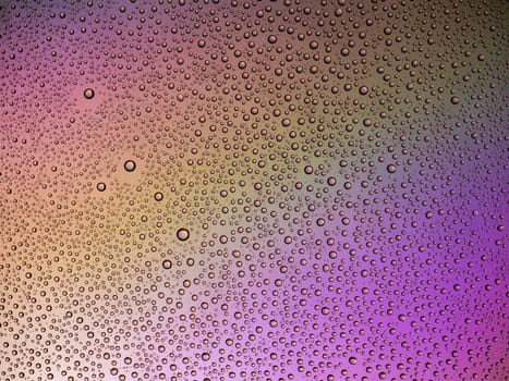 Water droplets on the glass with a colored background. Drops of water.